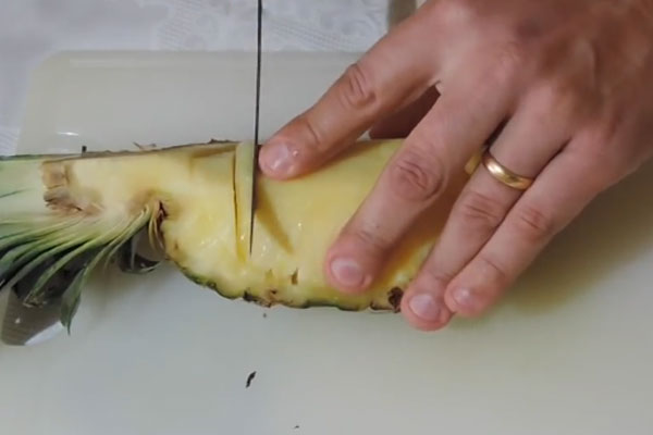 Сверху вниз аккуратно режем ананас на ломтики